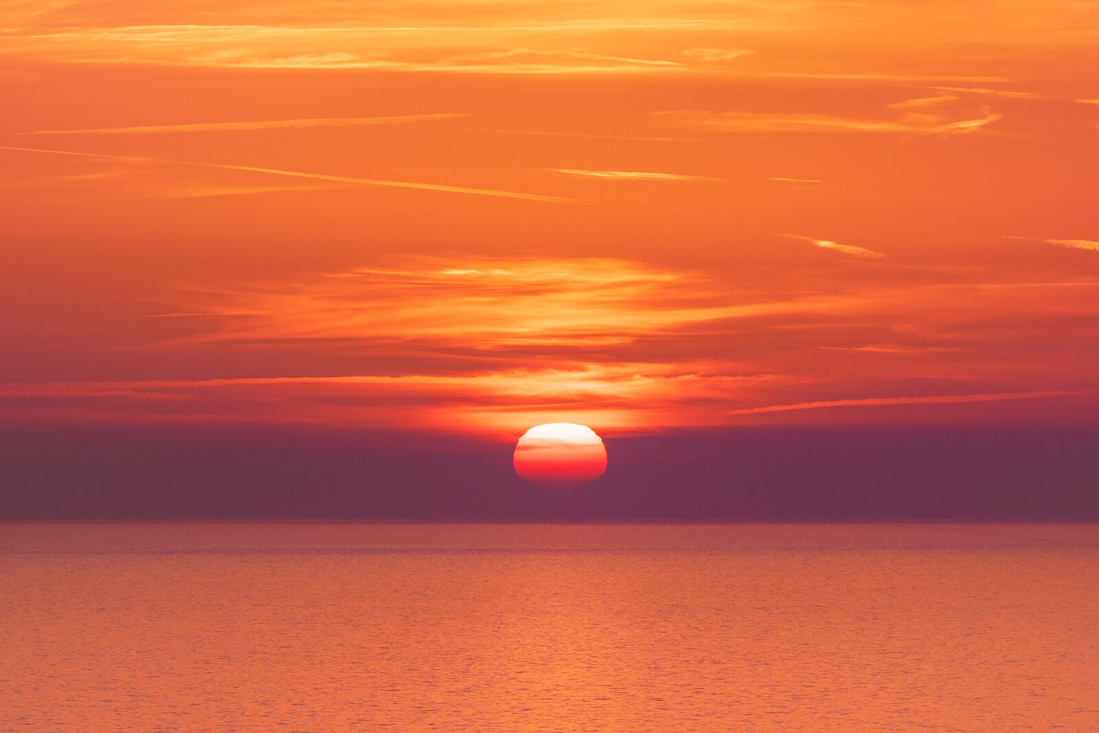 sunset over smooth ocean with orange sky